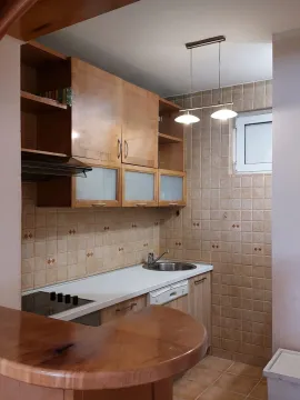 Kuhinja sa drvenim elementima, svijetlim radnim površinama i pločicama. - image 12
