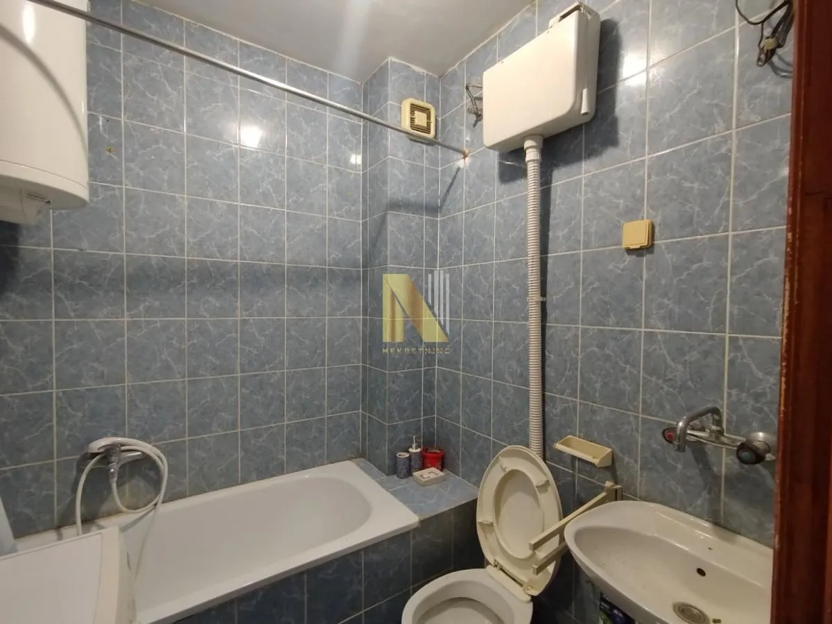 Manje kupatilo sa plavim pločicama, kadom, toaletom i umivaonikom.