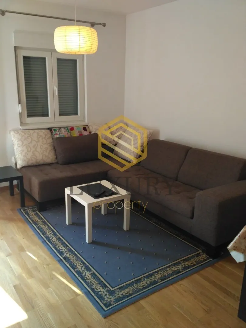 Dnevna soba sa ugaonom garniturom i tepihom.