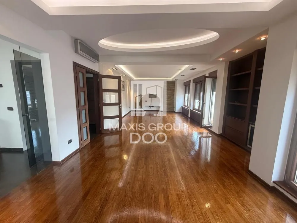 Spacious bright living room with wooden flooring and built-in shelving.