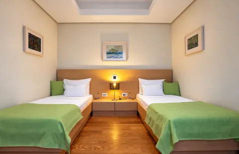 Bedroom with two single beds and a nightstand in the middle. - image 9