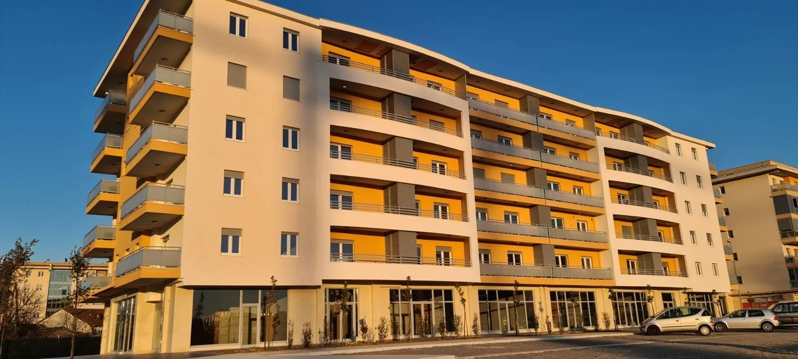 Eksterijer moderne stambene zgrade sa žutom fasadom.