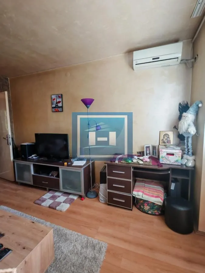 Dnevna soba sa televizorom, komodom i klima uređajem.