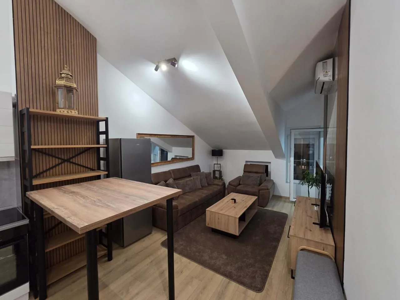Living room with a sofa, dining table, and sloped ceiling.