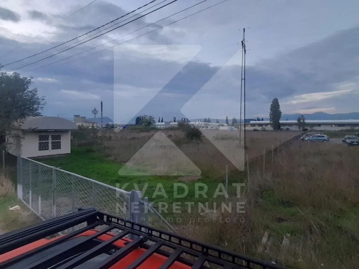 Pogled na plac i okolno zemljište sa ogradom.