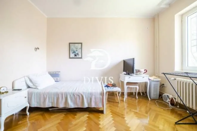 Smaller bedroom with a bed, desk, and parquet flooring.
