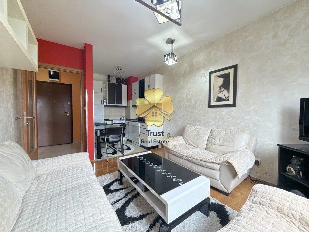 Living room with a sofa and dining area in the background.