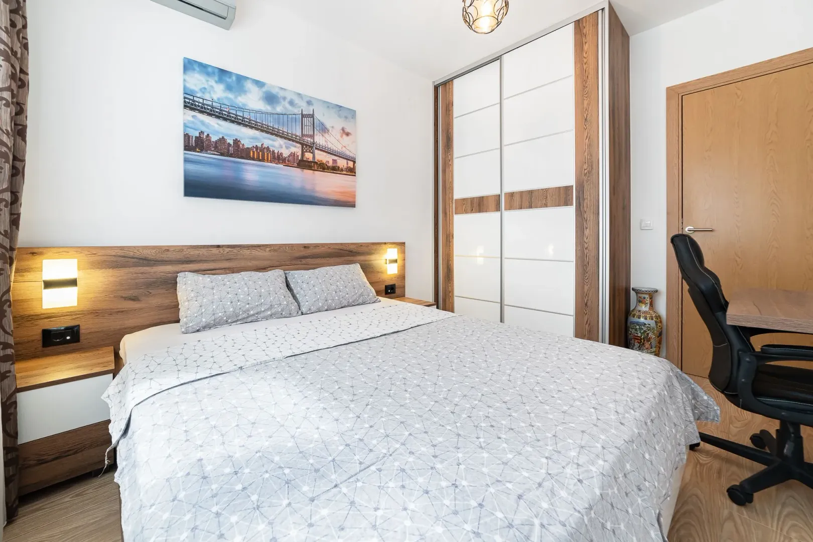 Furnished bedroom with a double bed, wardrobe, and a desk.