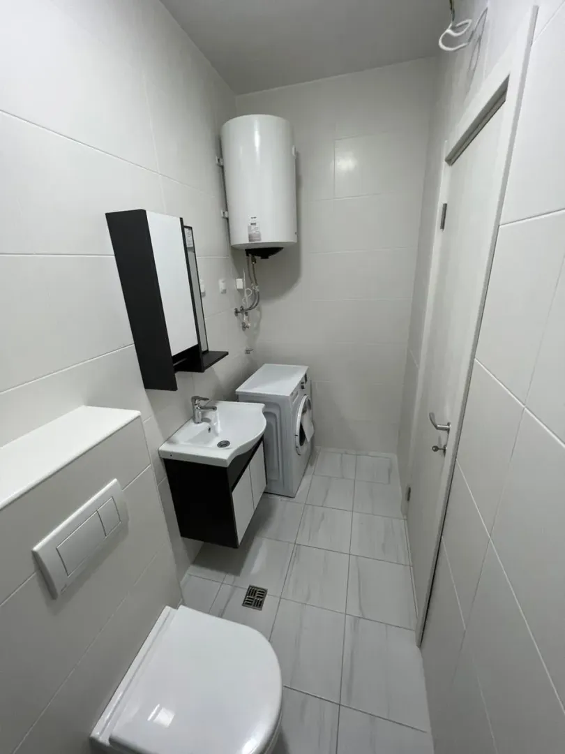 Svijetlo kupatilo sa veš mašinom i bojlerom.