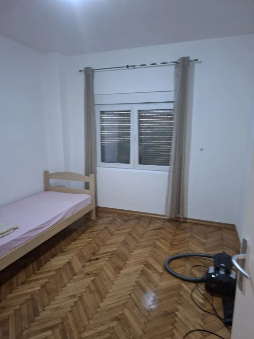 Bright bedroom with a single bed and parquet floor.