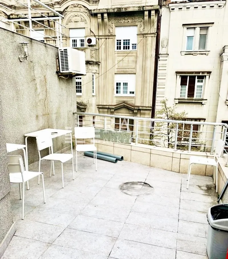 Spacious terrace with patio furniture and a view of surrounding buildings.