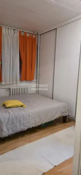 Furnished bedroom with a double bed, wardrobe, and a window with orange curtains. - image 4
