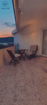 Namještena terasa sa stolom i stolicama i pogledom na more u sumrak. - image 4