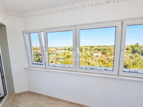 Enclosed balcony with a view of greenery and the city. - image 5