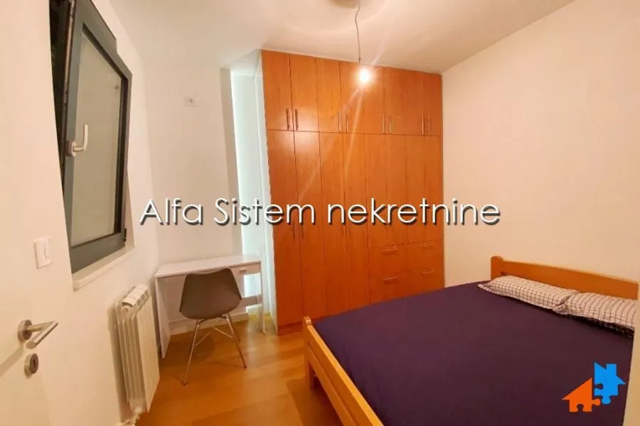 Furnished bedroom with a double bed, large wooden wardrobe, and a desk.
