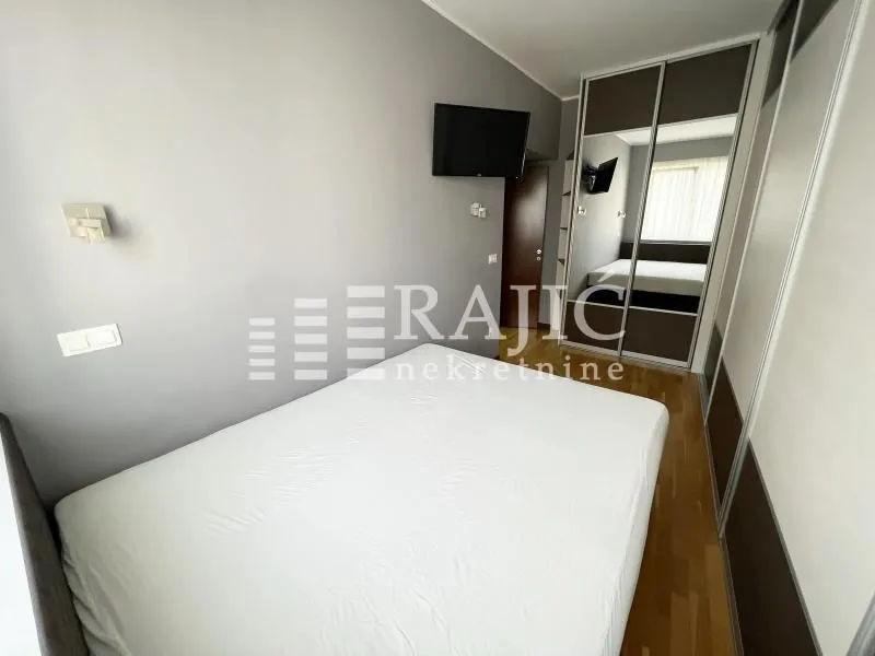Furnished bedroom with a double bed and a built-in mirrored wardrobe.