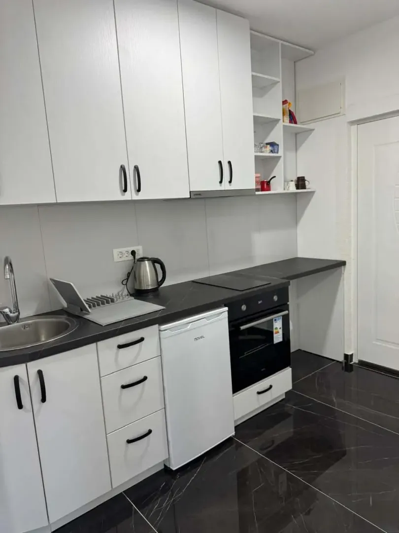 Modern kitchen with white cabinets and a dark countertop.