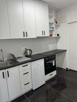 Modern kitchen with white cabinets and a dark countertop. - image 4
