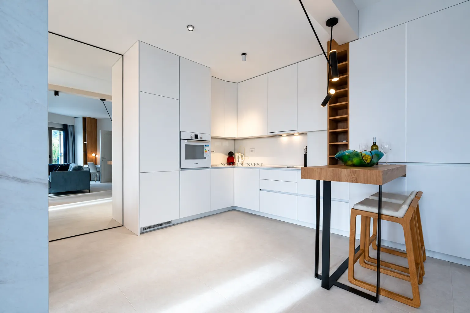 Modern white kitchen with a breakfast bar and built-in appliances.