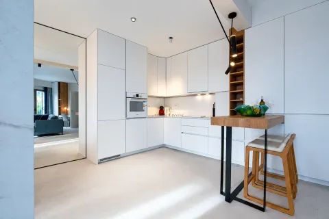 Modern white kitchen with a breakfast bar and built-in appliances. - image 5