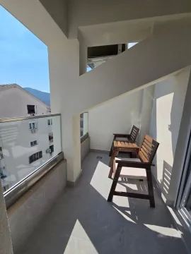 Natkriveni balkon sa drvenim stolicama i pogledom na okolne zgrade i brda. - image 7