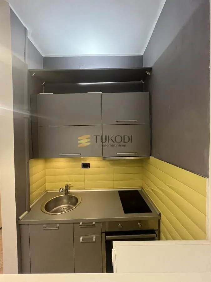 Small kitchen with a sink, built-in cooktop, oven, and grey cabinets.