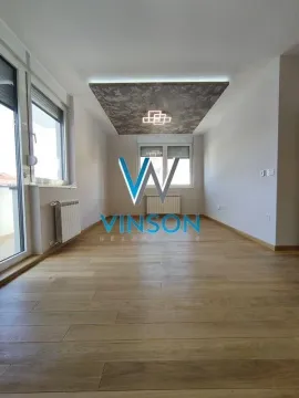 Empty living room with wooden flooring and a dropped ceiling with lighting. - image 2