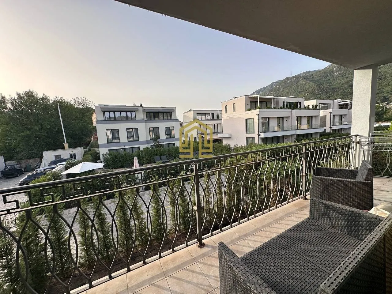 Namtještena terasa sa garniturom za sjedenje i pogledom na okolne zgrade i brda.
