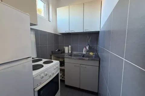 Manja kuhinja sa belim elementima, šporetom i sudoperom obložena sivim pločicama. - image 3