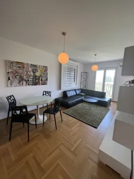 Svijetla dnevna soba sa crnom ugaonom garniturom i trpezarijskim stolom. - image 3