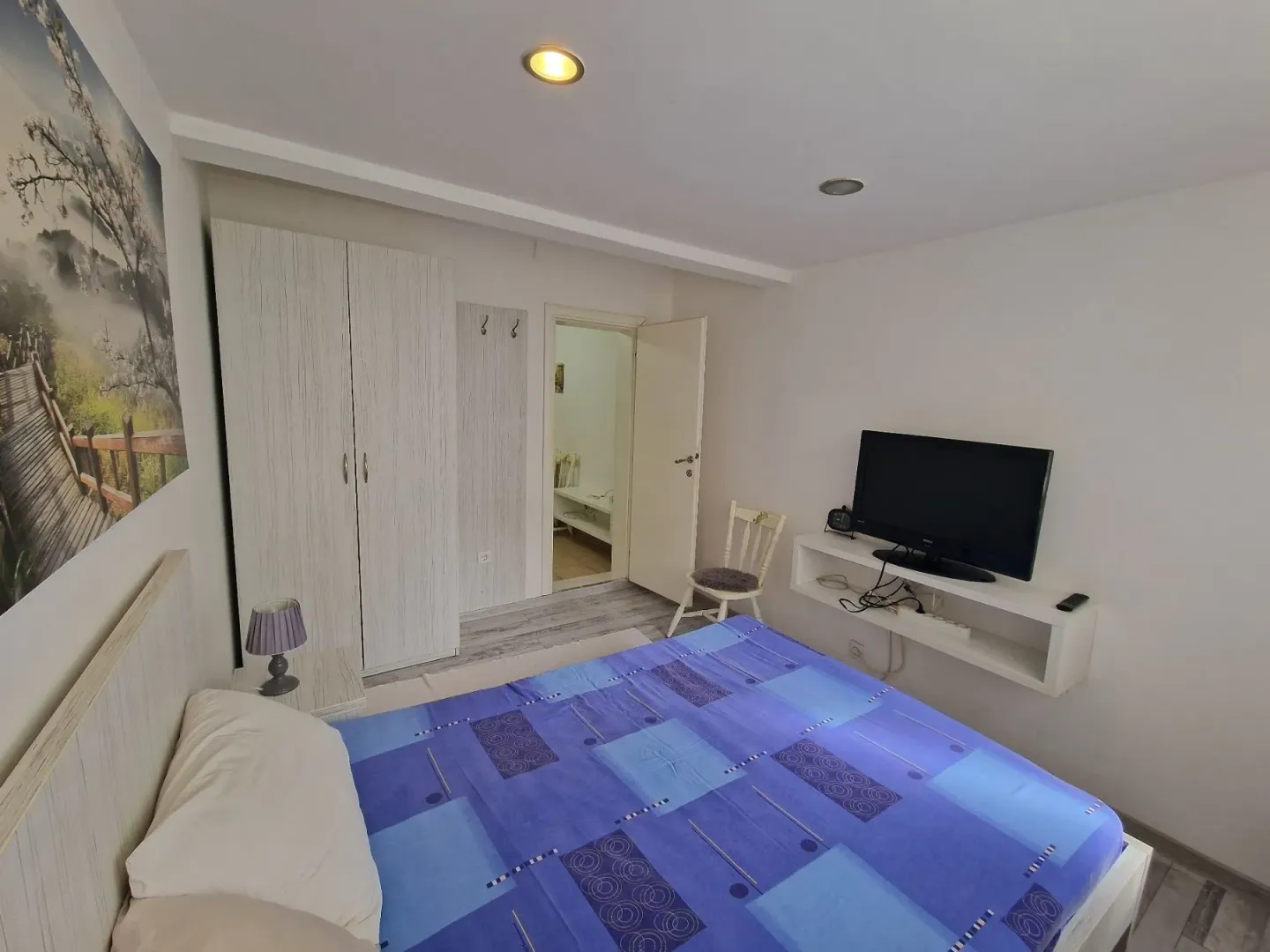 Furnished bedroom with a double bed, wardrobe, and television.