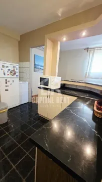 Kuhinja sa crnim mermernim radnim površinama i belim elementima. - image 9