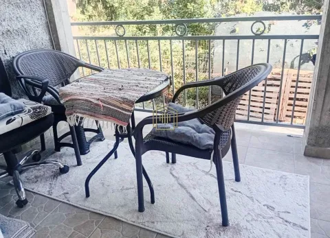 Small table and two chairs on a covered balcony with a metal railing. - image 2