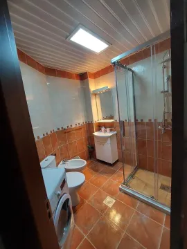 Bathroom with a shower cabin, washbasin, toilet, and washing machine. - image 7