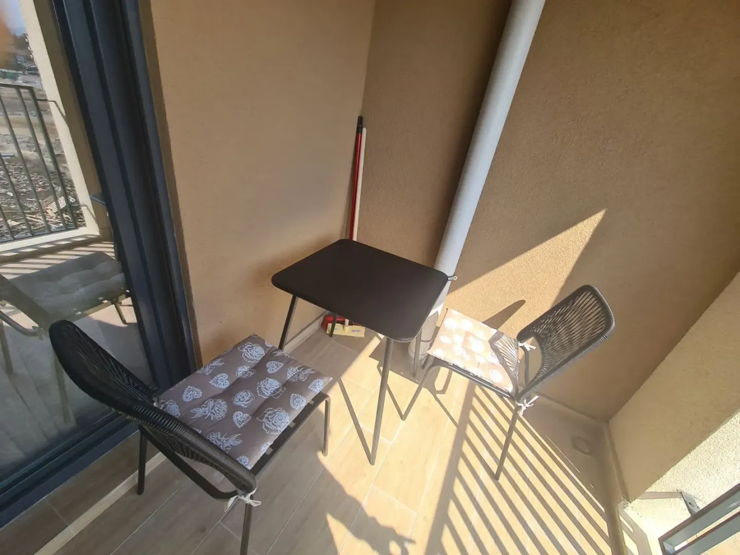 Small furnished balcony with a small table and two chairs.
