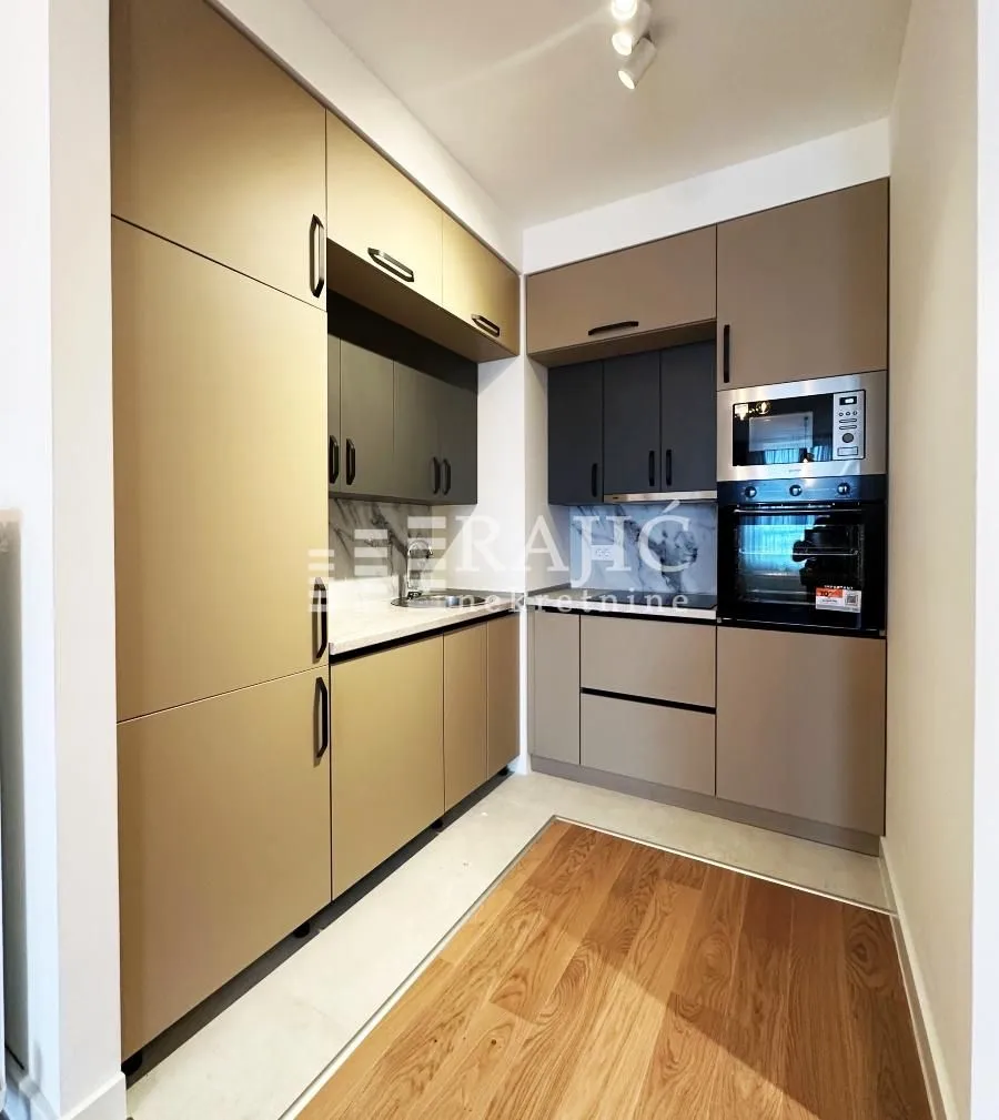 Modern and equipped kitchen with built-in appliances and wooden flooring.