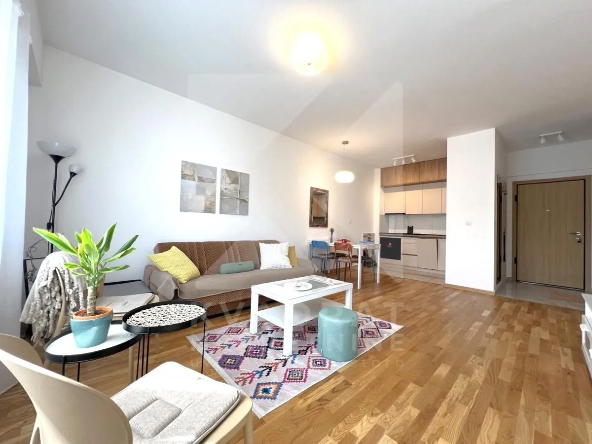 Living room with a sofa, coffee table and an open kitchen in the background.