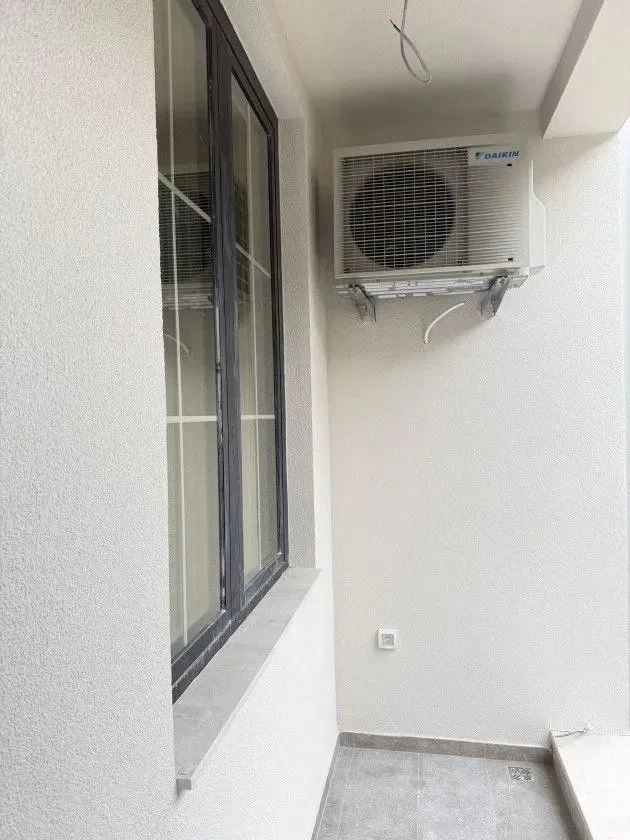 Small balcony with an outdoor air conditioning unit and a window.