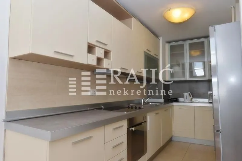 Modern kitchen with beige cabinets and built-in appliances.