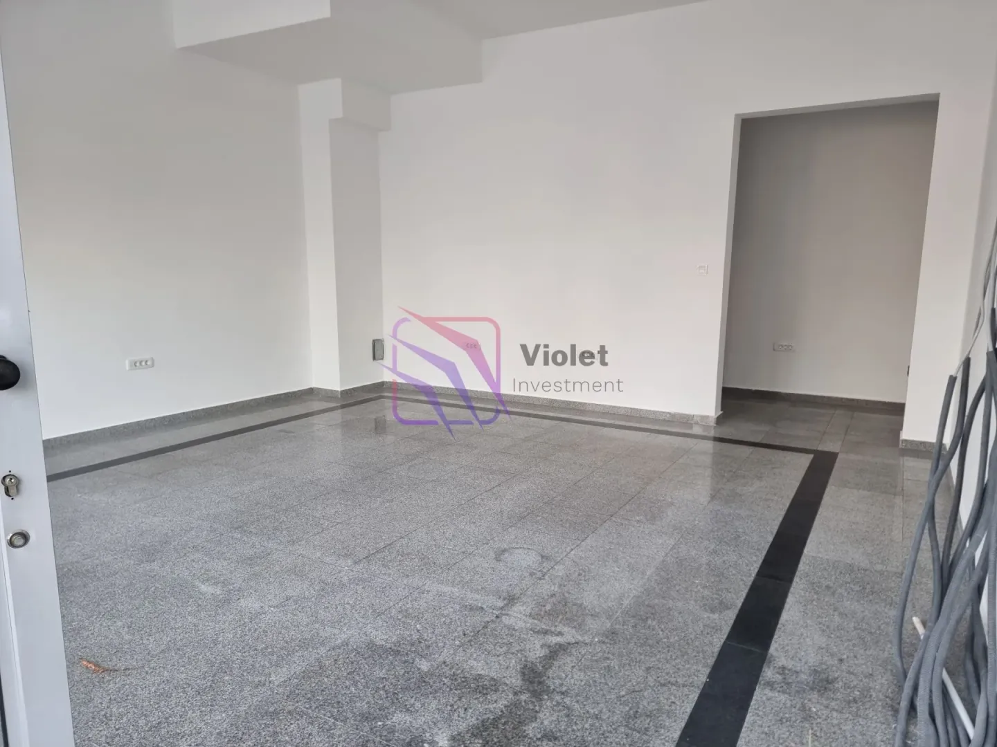 Empty unfurnished room with light walls and grey floor tiles.