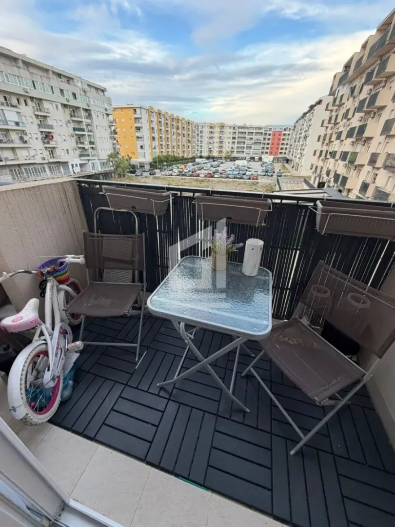 Namješten balkon sa stolom, stolicama i pogledom na naselje.