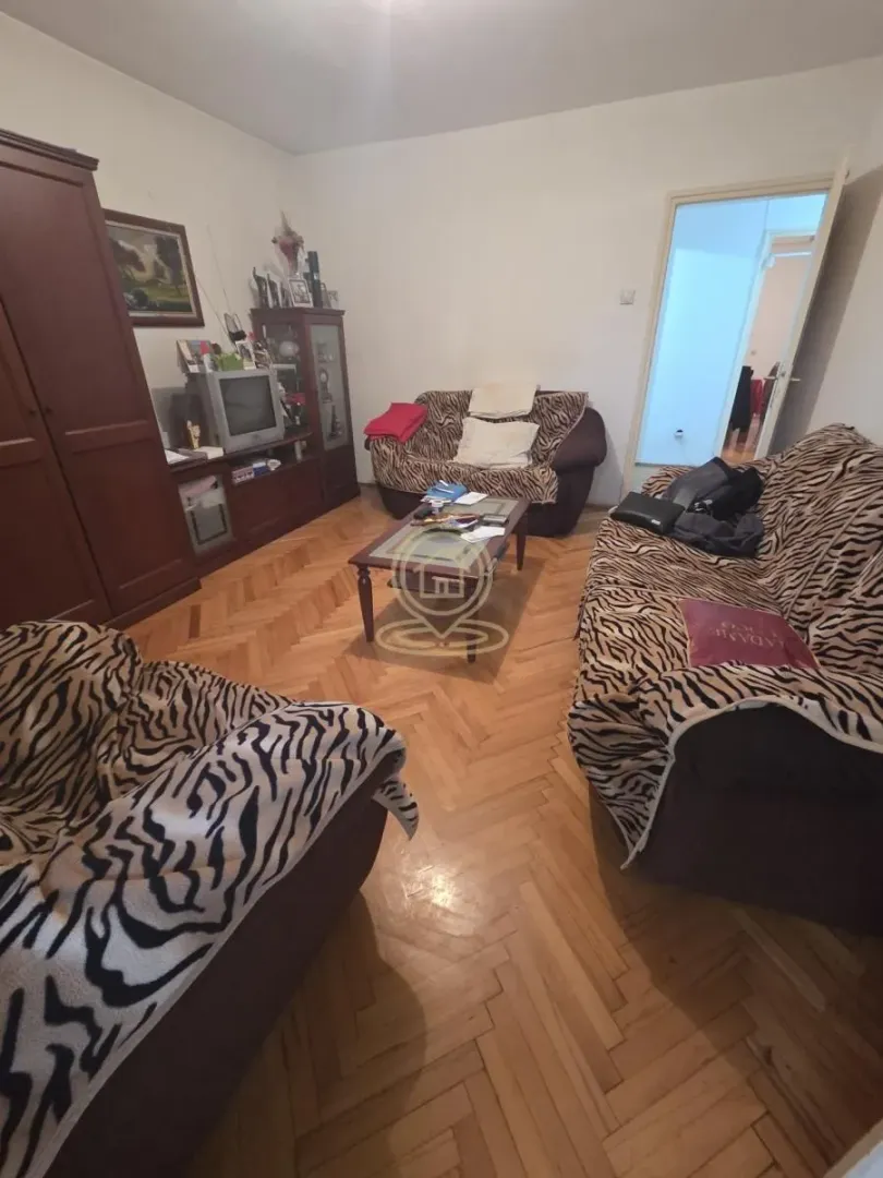 Dnevna soba sa garniturom, drvenim nameštajem i parketom na podu.