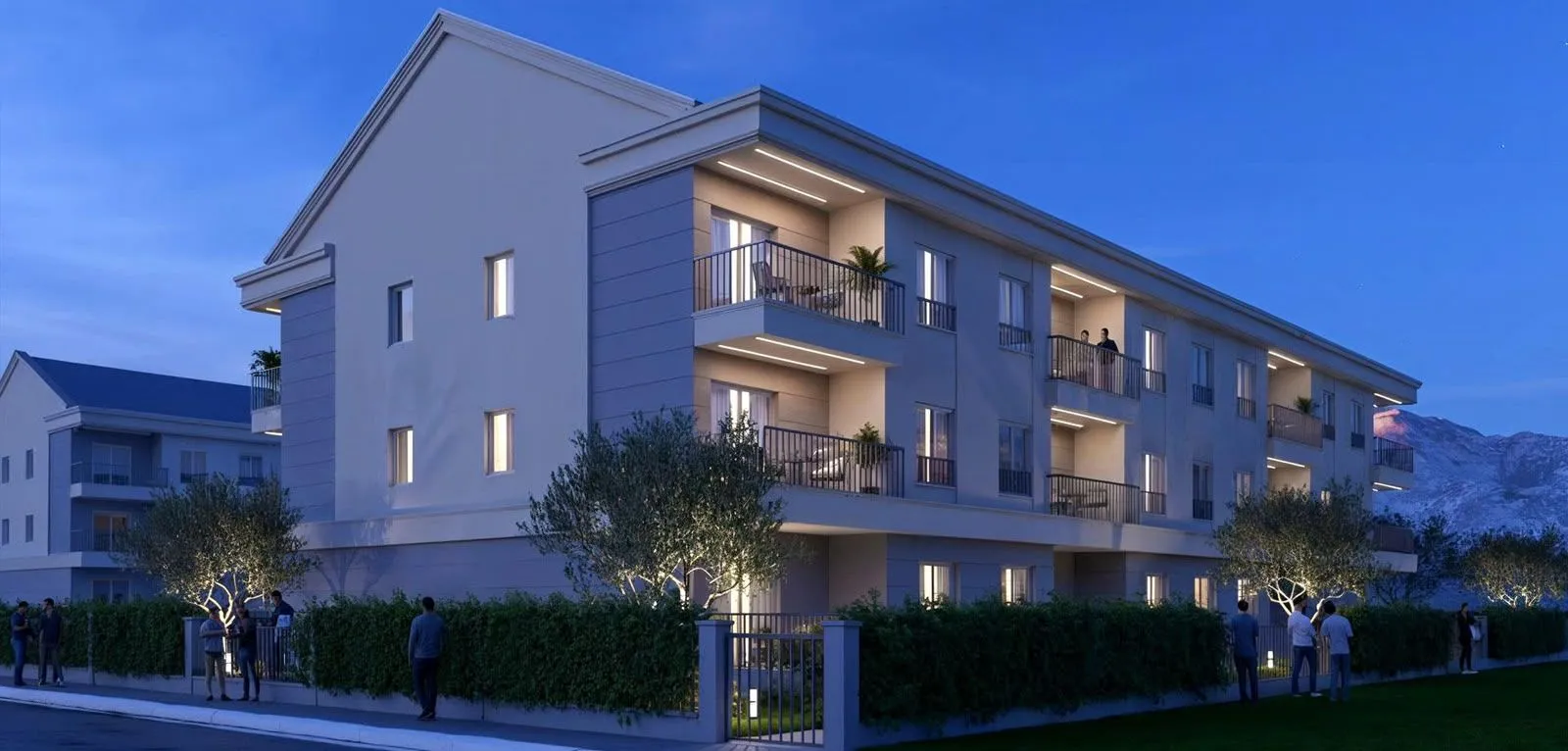 Eksterijer moderne stambene zgrade noću sa osvijetljenim balkonima i dvorištem.