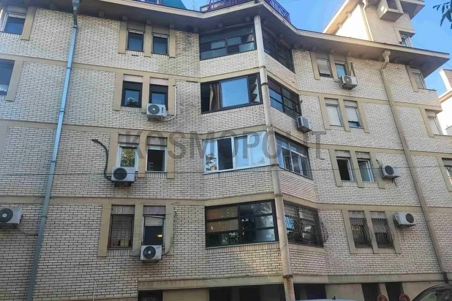Pogled na fasadu stambene zgrade od cigle sa više prozora i klima uređaja.
