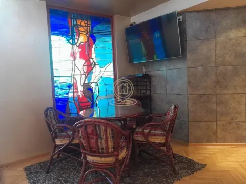 Living room with a dining table, a large stained glass window and a wall-mounted TV. - image 3