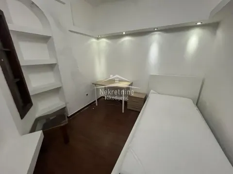 Small bedroom with a single bed, a desk, and built-in shelves. - image 8