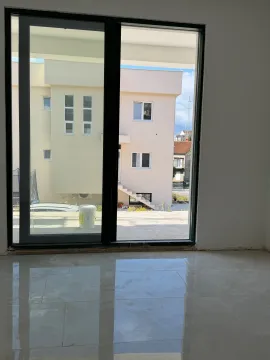 View through a large balcony door towards the exterior space and neighboring houses. - image 10