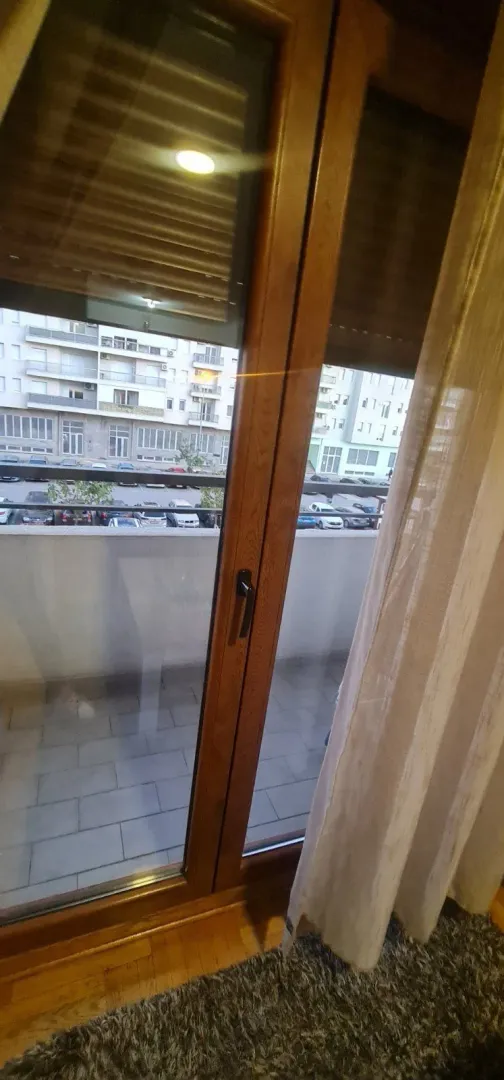 Pogled kroz balkonska vrata prema terasi i susjednim zgradama.