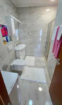 Kupatilo obloženo keramičkim pločicama sa tuš kabinom, umivaonikom i wc šoljom. - image 11