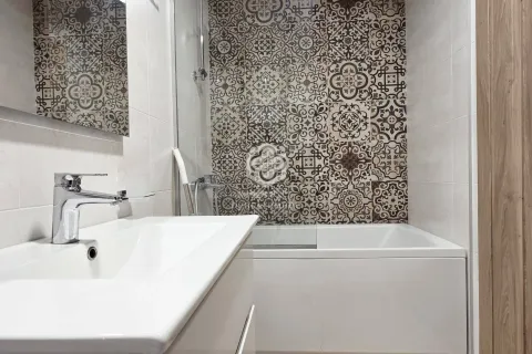 Modern bathroom with a washbasin and a bathtub decorated with patterned tiles. - image 5